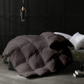 Dark quilted comforter on a bed in a room with dark paneled walls.