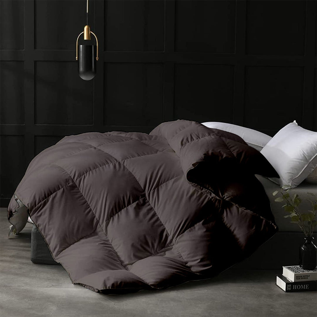 Dark quilted comforter on a bed in a room with dark paneled walls.