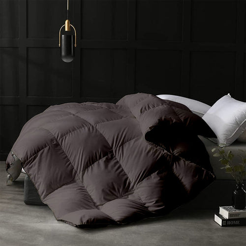 Dark quilted comforter on a bed in a room with dark paneled walls.